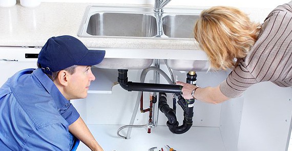 lady showing damage pipe in kitchen wash basin to a man plumber