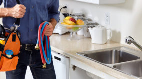 Plumber bringing new water hoses to work on kitchen sink
