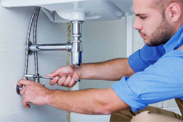 expert plumber working on drain pipe cleaning