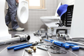 plumber working on plumbing repairs in a bathroom