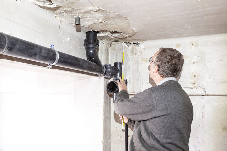 Underneath the ceiling in a room hang drain pipes of under construction and replacement
