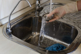 a person cleaning sink drain with rubber gloves