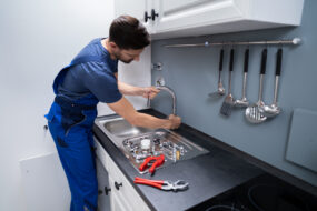 Male Plumber Fixing Faucet In Kitchen